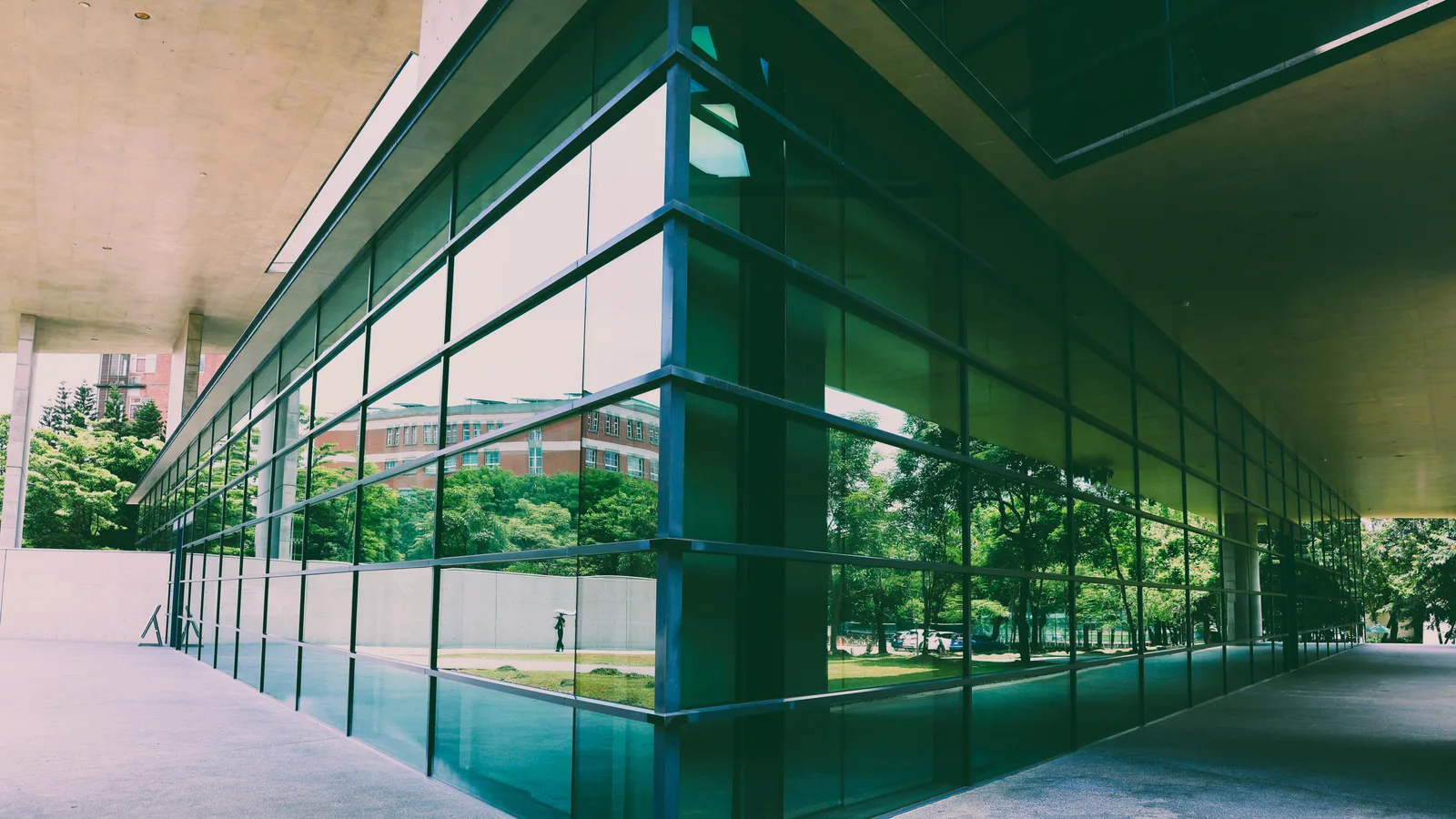 A modern commercial building with a reflective glass facade showcasing surrounding green landscape