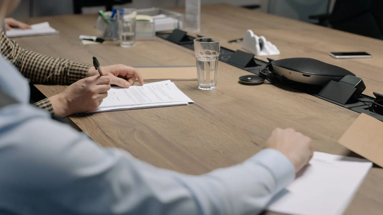Professional setting of a business meeting with individuals signing documents on a conference table