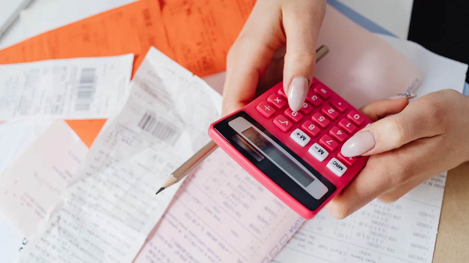 Calculator and paperwork on a desk, representing the break costs and fees to check before refinancing a commercial mortgage