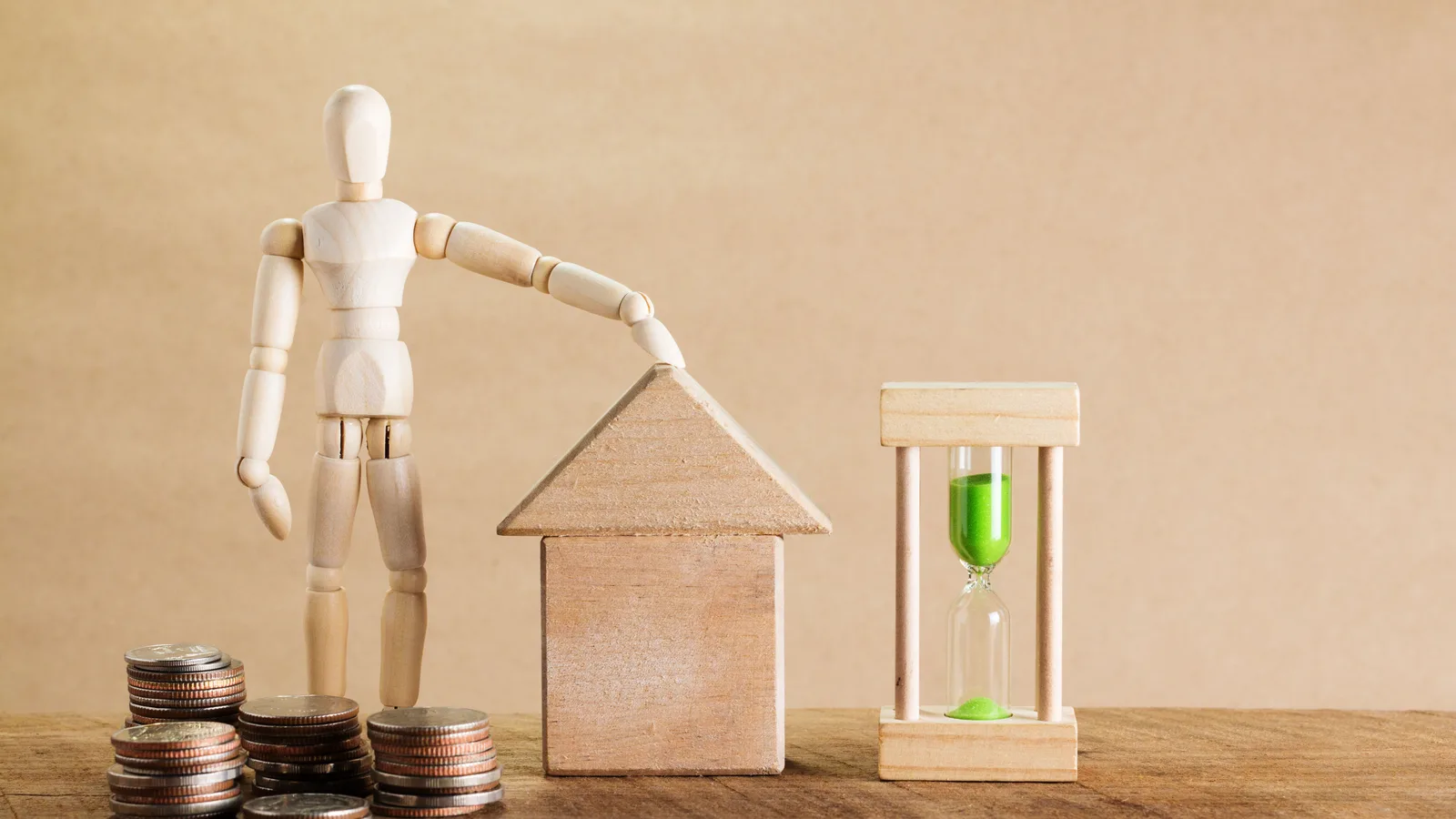Stack of coins beside a model house, representing the equity a business can release when refinancing a commercial mortgage