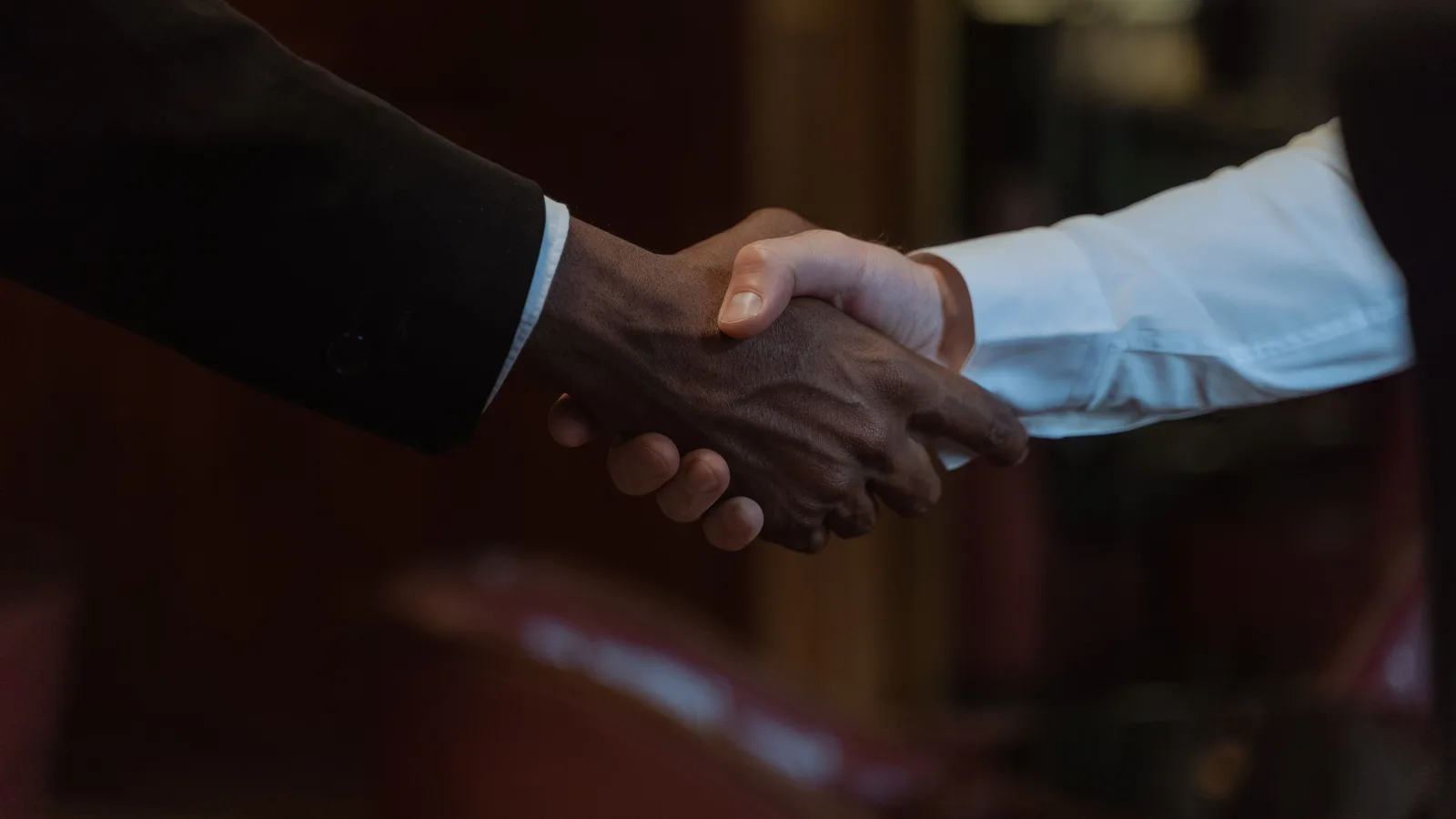 Two business people shaking hands over a signed agreement, representing settlement with a new lender on a refinanced commercial mortgage
