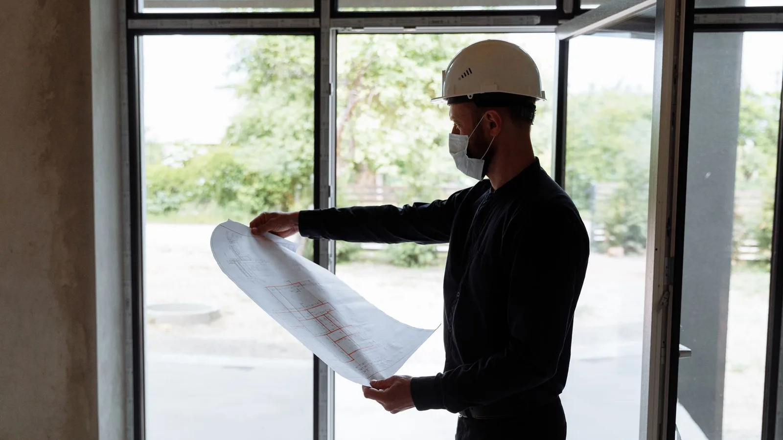 Site engineer and commercial building inspector reviewing property plans indoors
