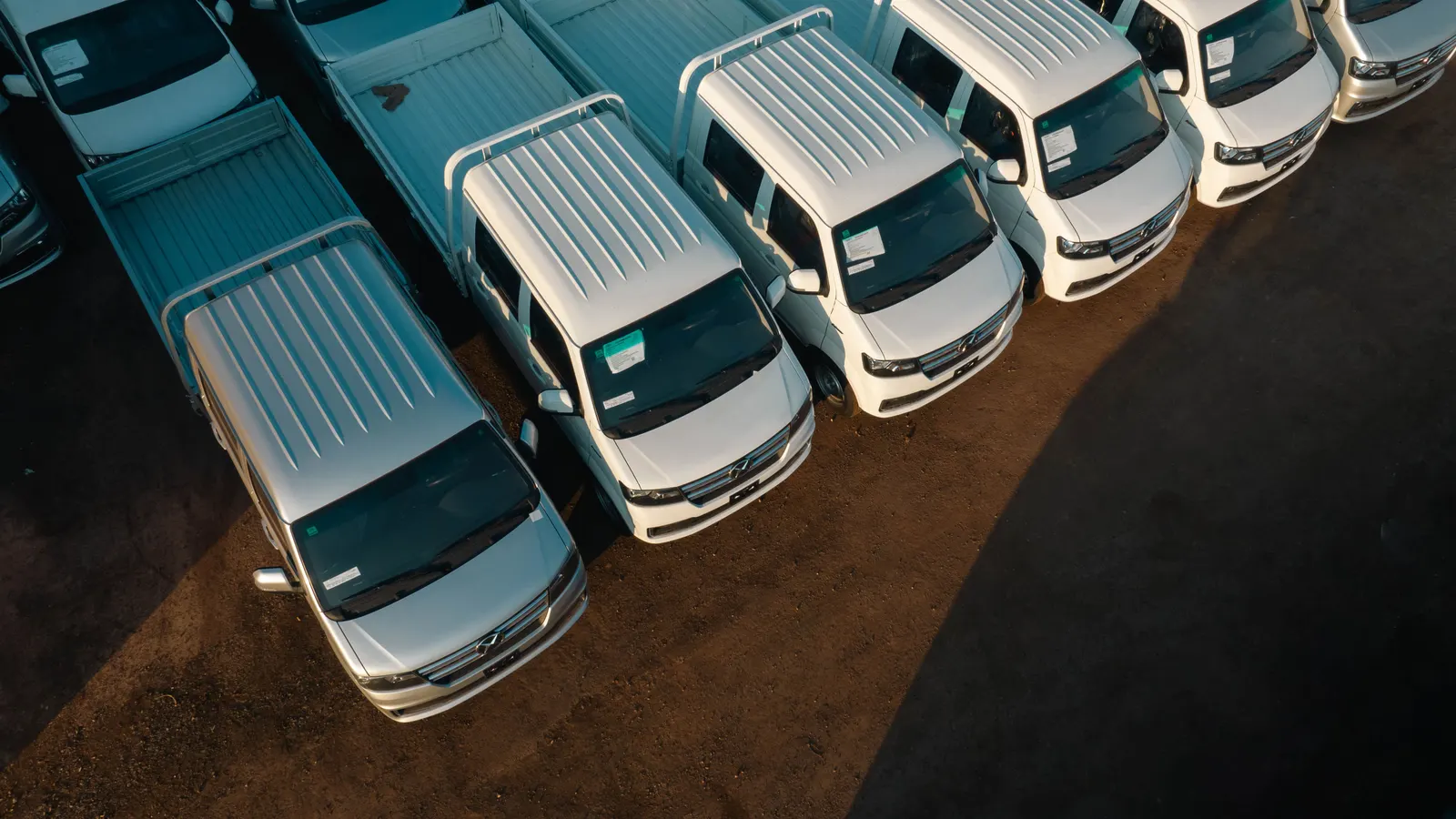 Aerial view of white commercial pickup trucks aligned in a row, the type of vehicle funded through commercial vehicle finance