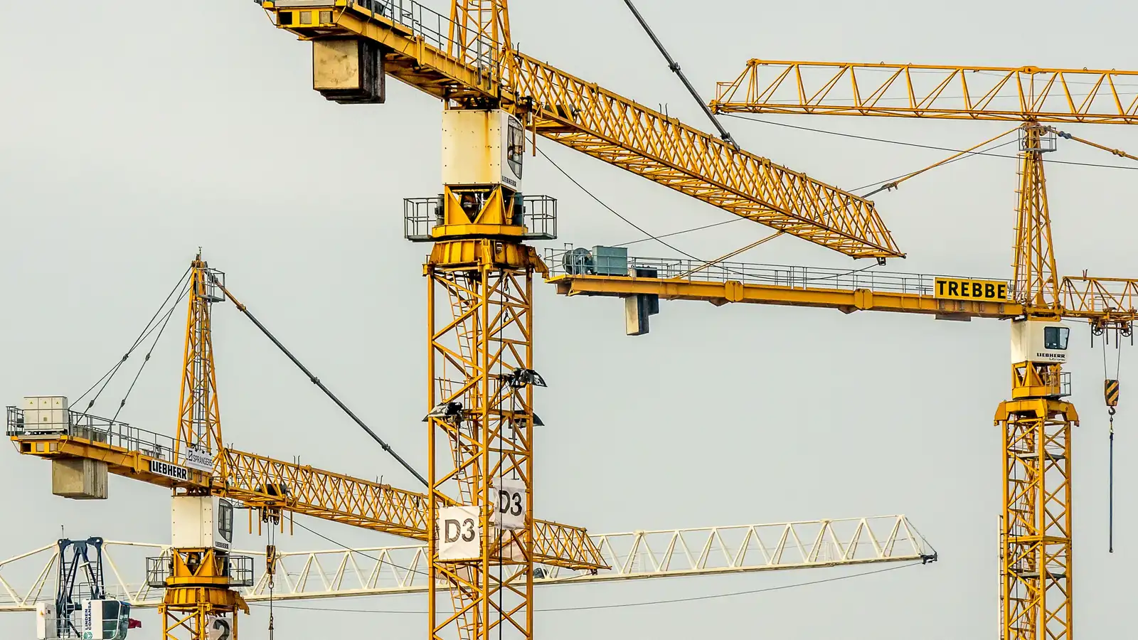 Yellow tower cranes against a blue sky on a construction site