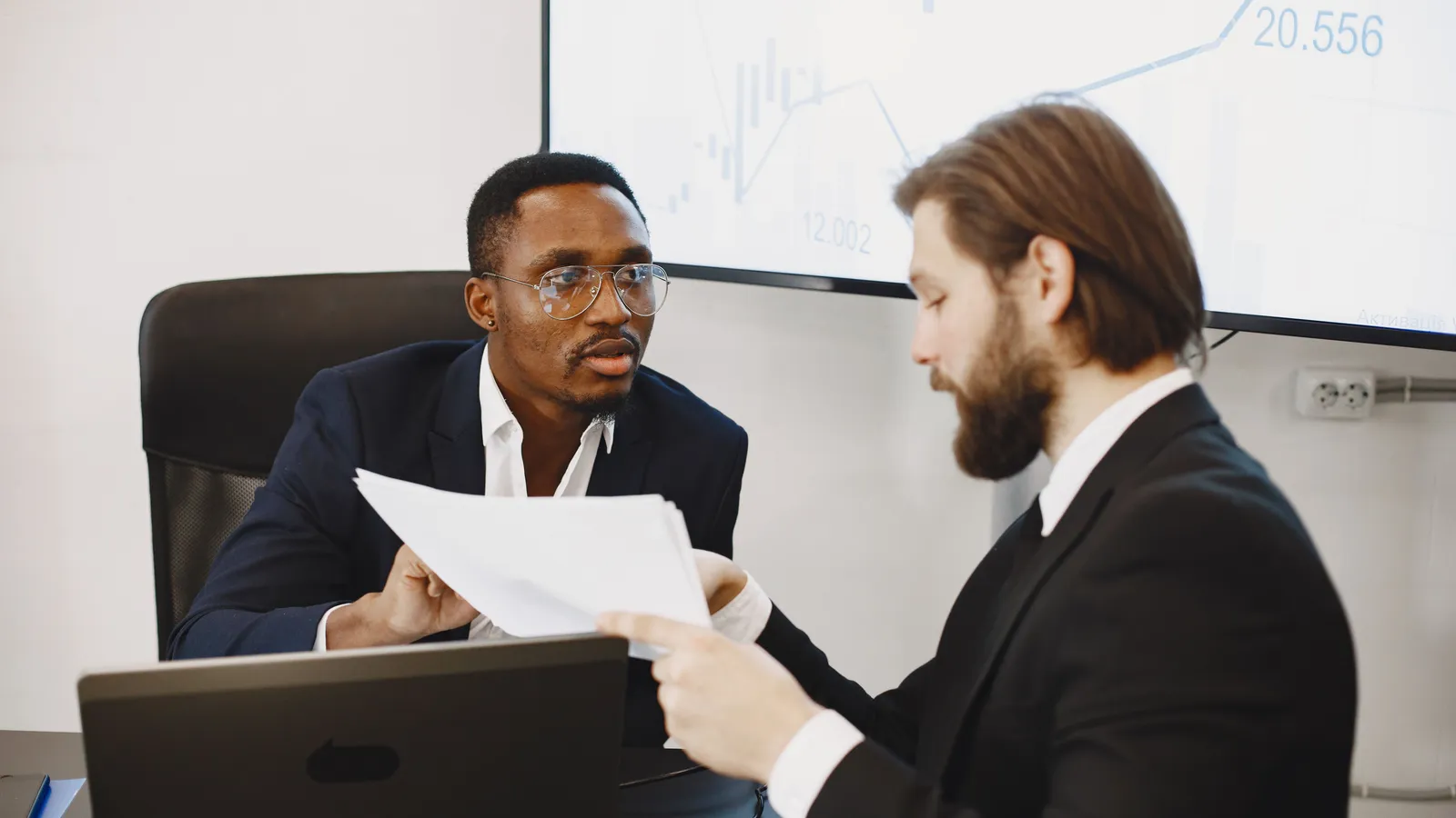 Two business professionals discussing paperwork in an office