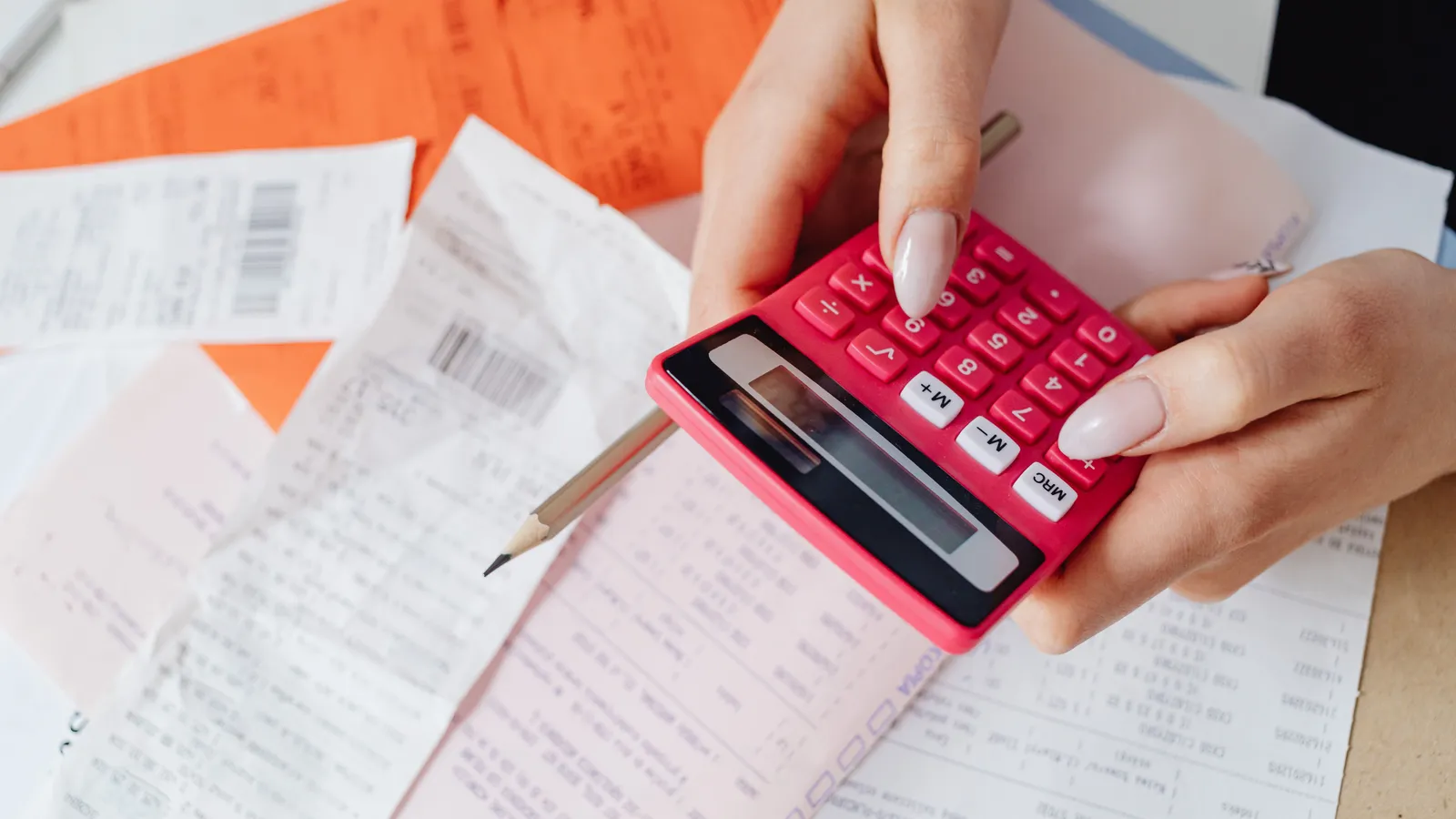 Person using a calculator while reviewing receipts at a desk
