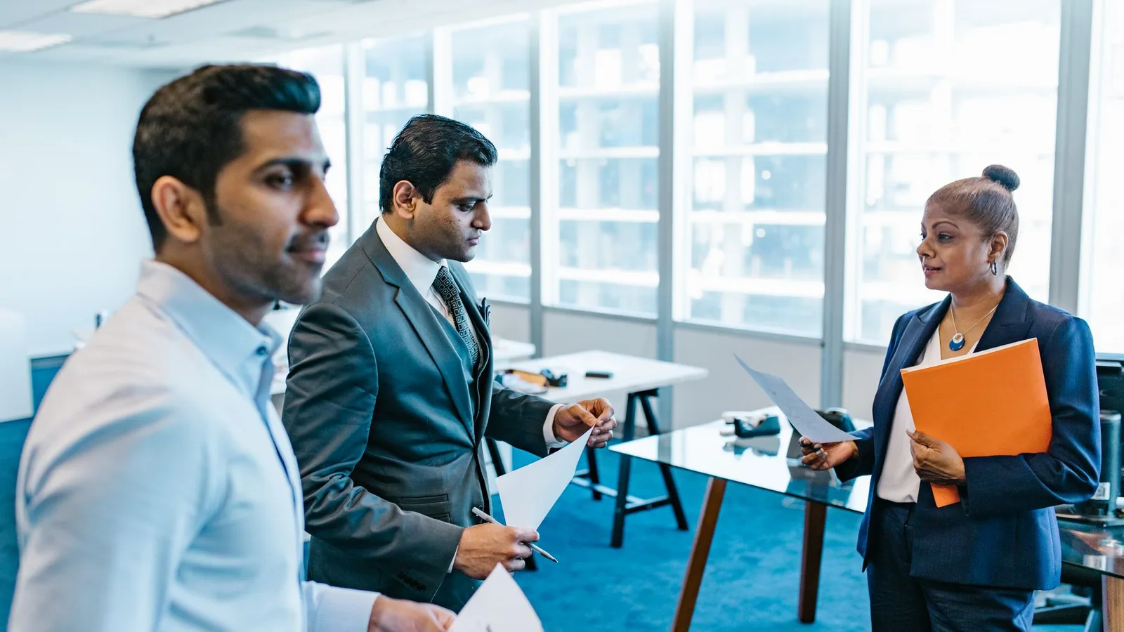 Business professionals discussing documents in a modern office environment, representing lender selection
