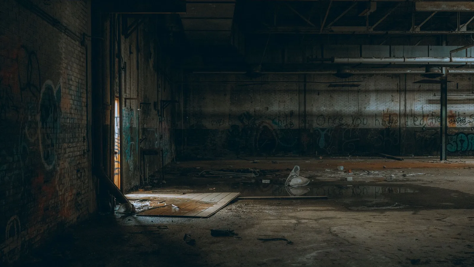 Dimly lit interior of an abandoned warehouse featuring graffiti and debris, showing scenarios where equipment finance isn't suited