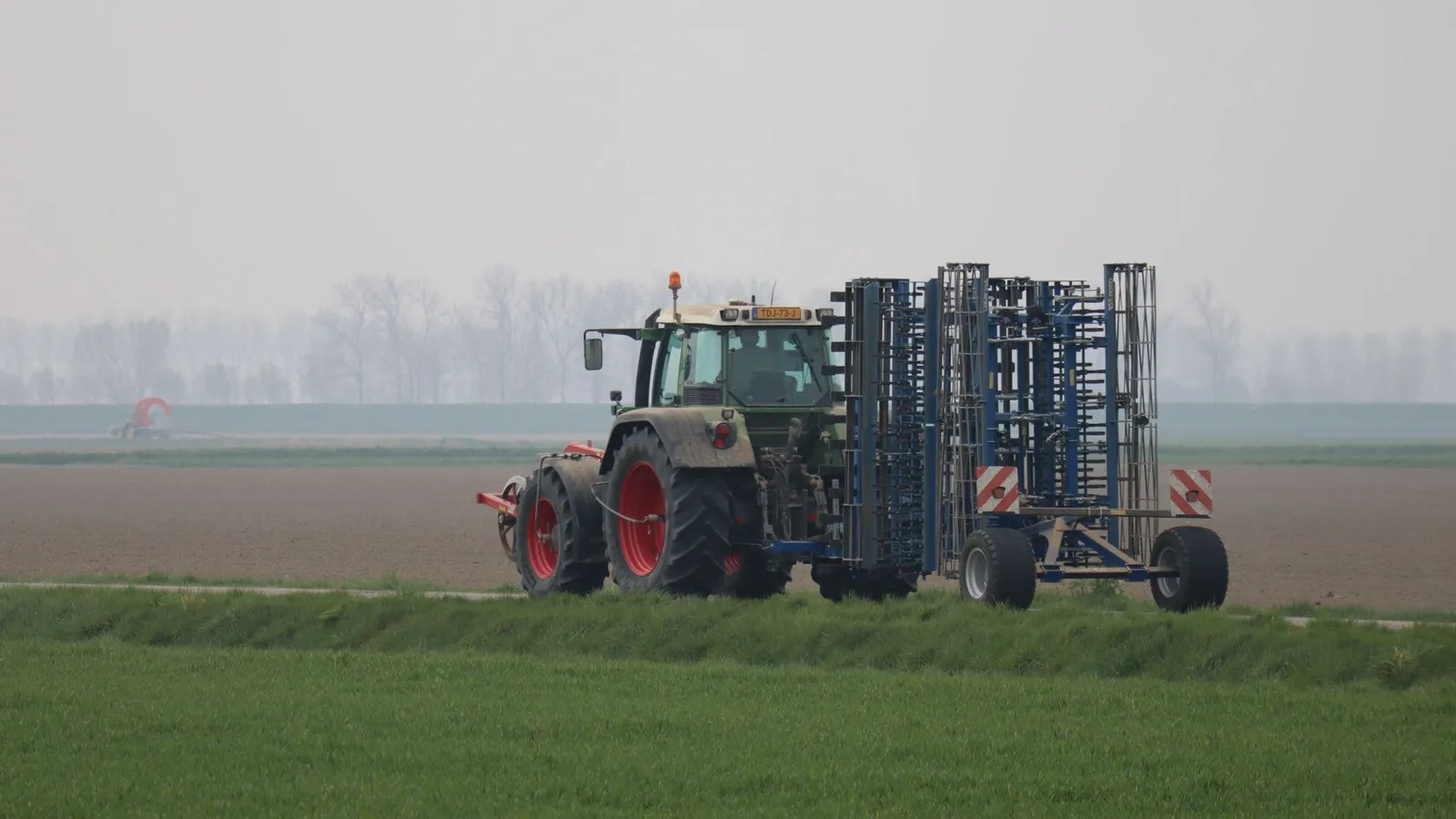 Red tractor driving across open farmland, the type of machine funded through farm equipment financing in NZ