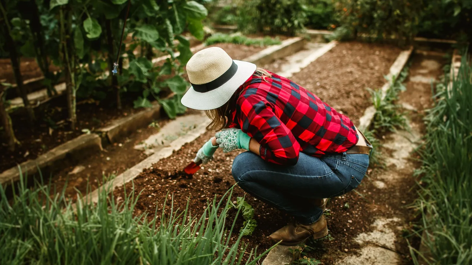 Woman tending a small home garden with hand tools, representing hobby or lifestyle-block use that falls outside farm equipment financing