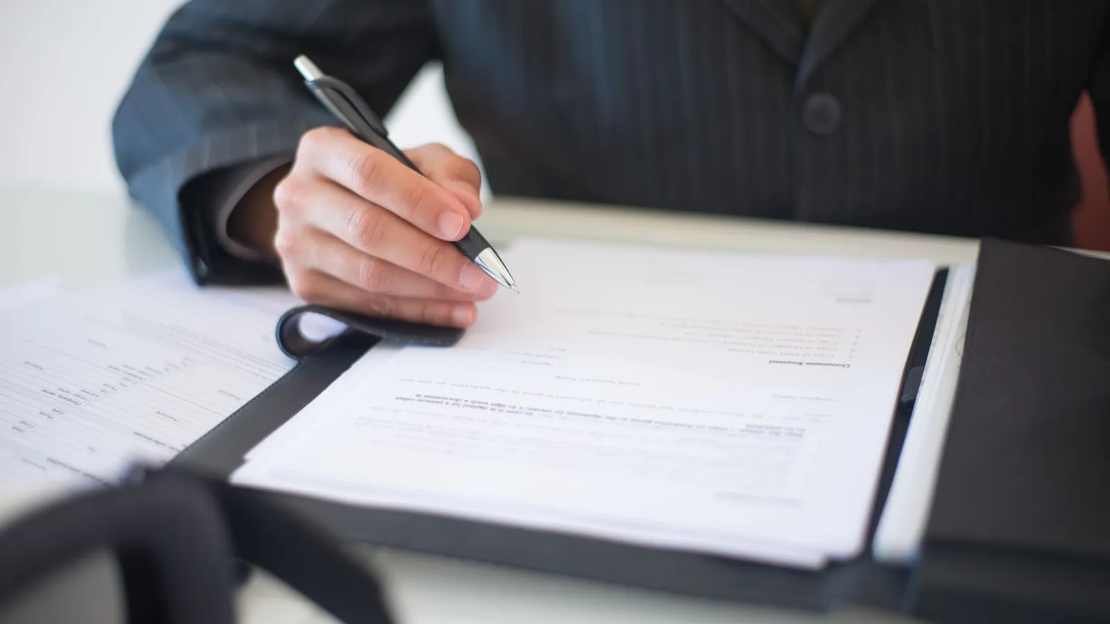 Person signing finance paperwork at a desk