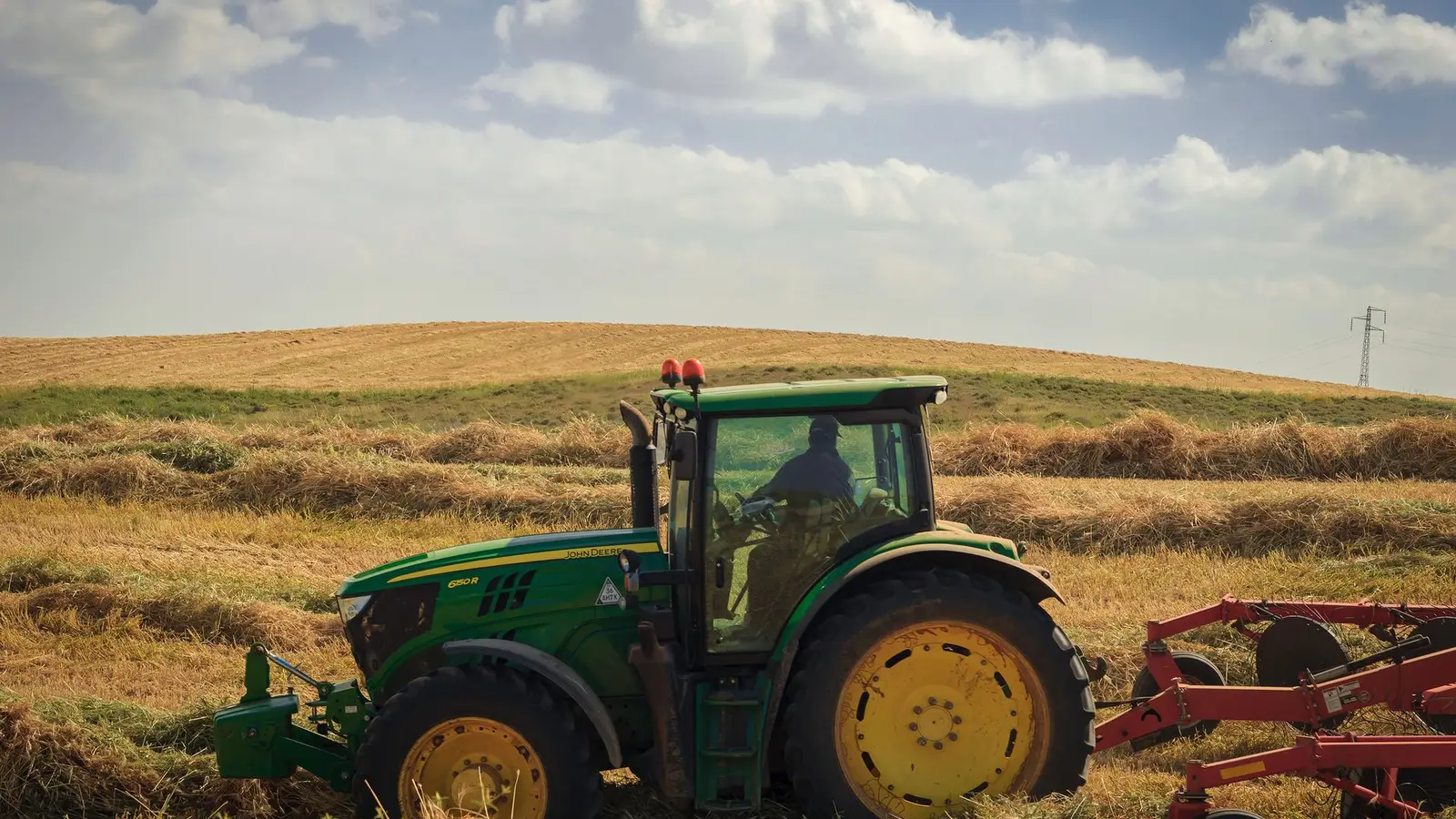 Farmer driving a tractor across a hay field, the type of work farm equipment financing supports