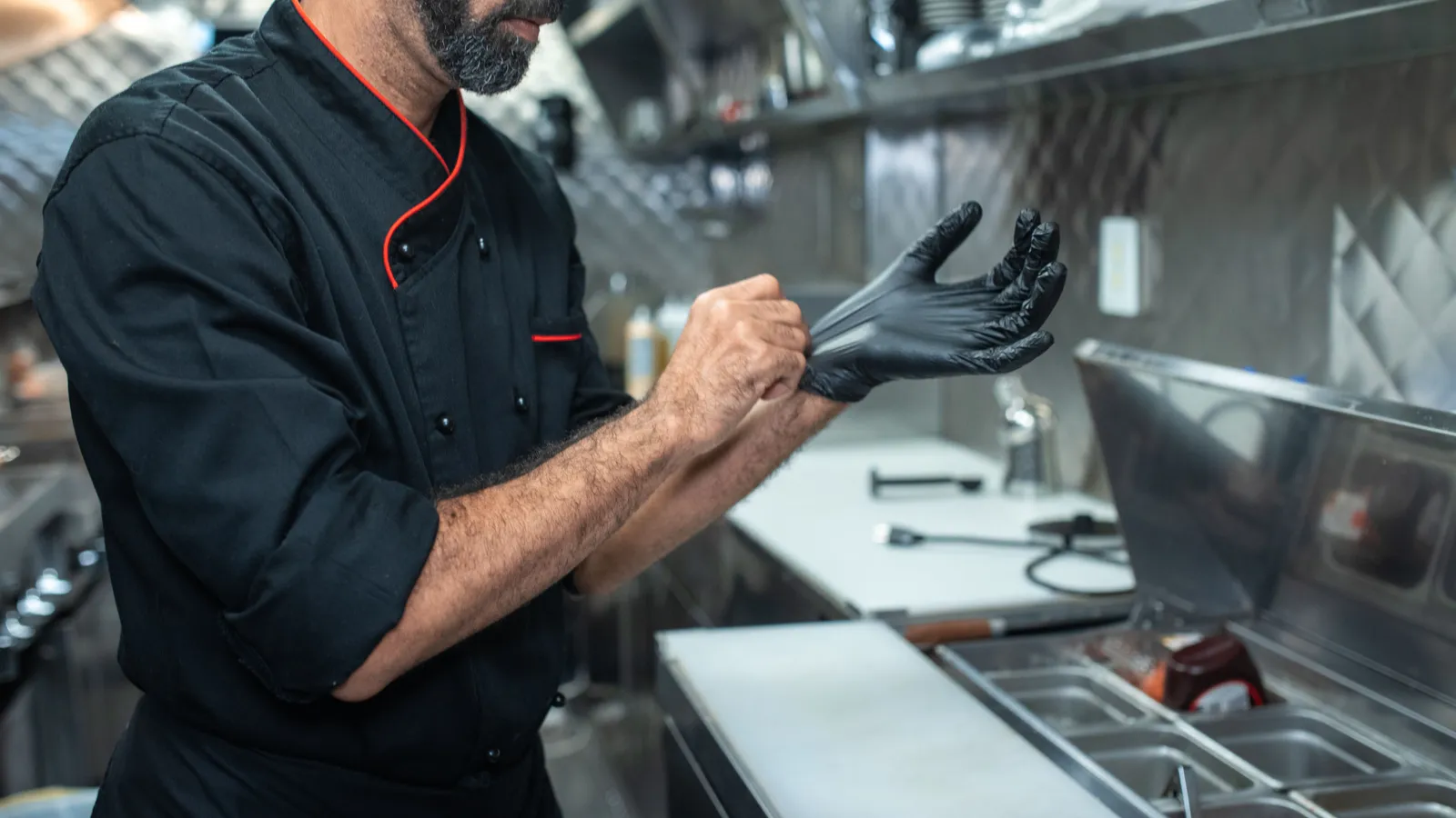 Chef putting on gloves in a professional kitchen, representing the food safety standards a food truck must meet before financing settles