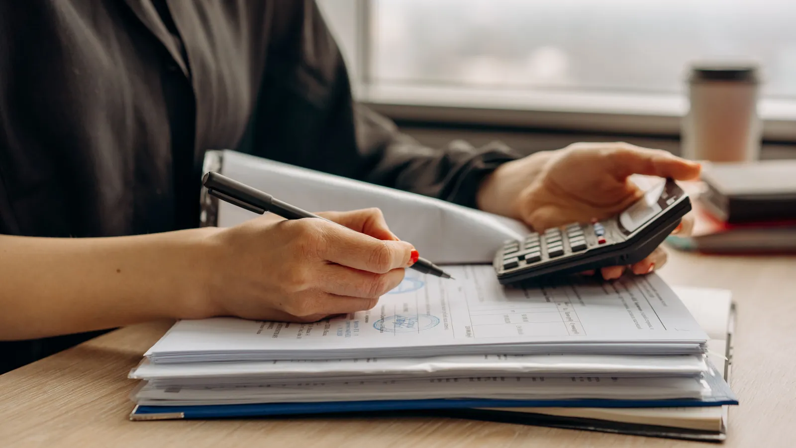 Close-up of a person using a calculator with financial paperwork in an office, the kind of documentation needed to qualify for food truck financing