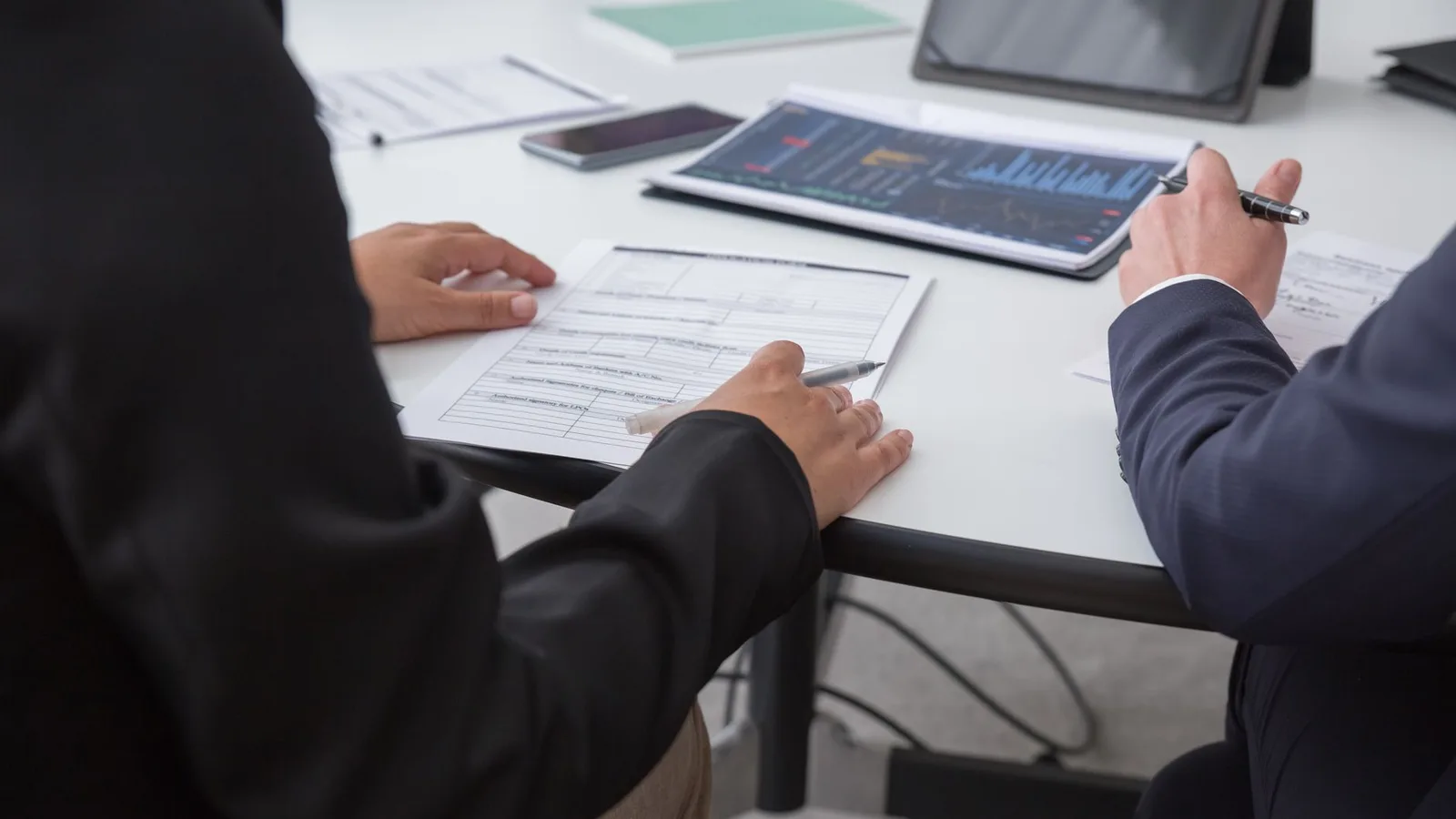 Close-up of finance professionals reviewing settlement documents in an office setting