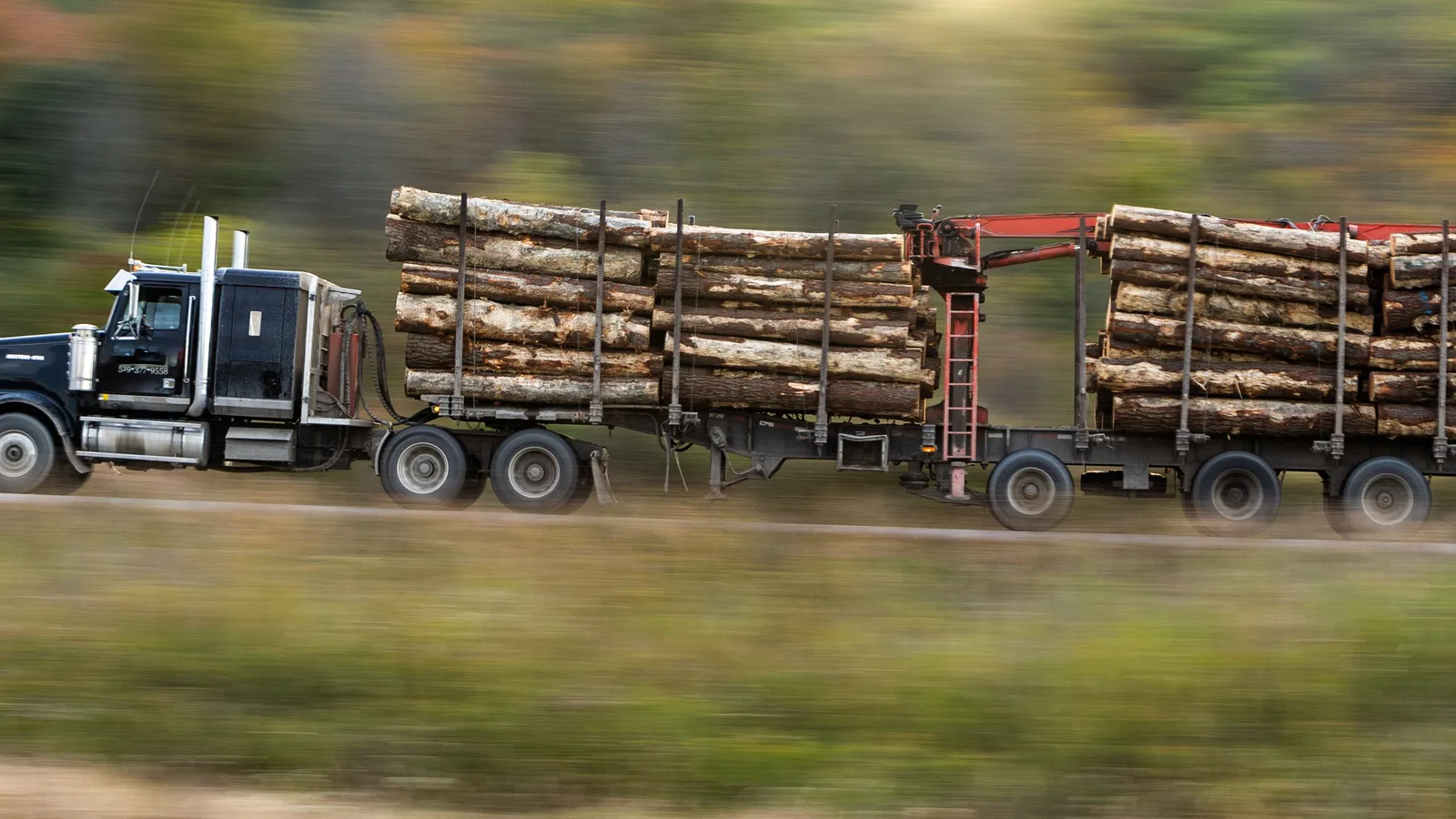 Logging transport truck hauling timber on a highway in New Zealand, showing commercial equipment loan structuring