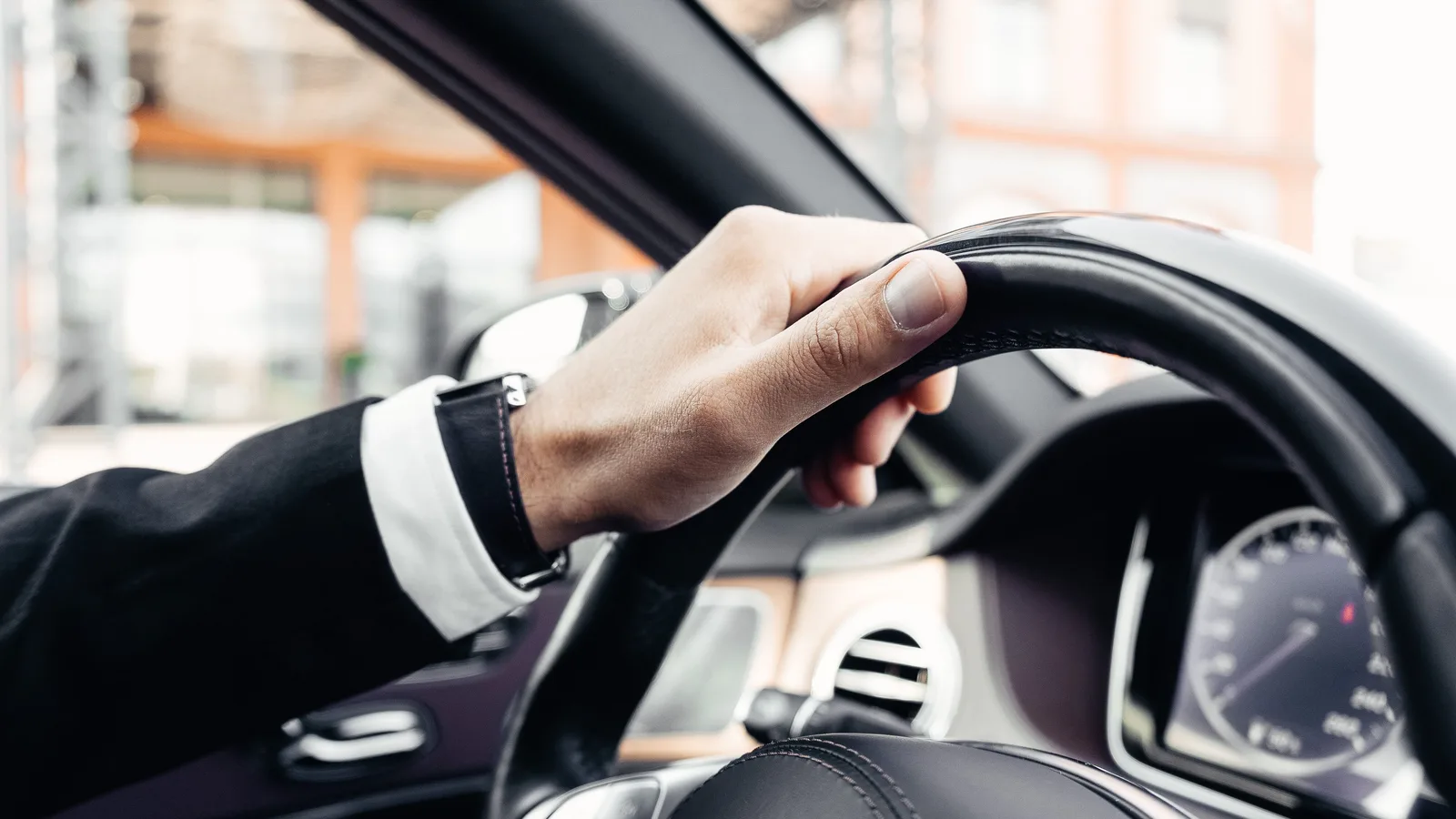 A businessman driving a car along an open road