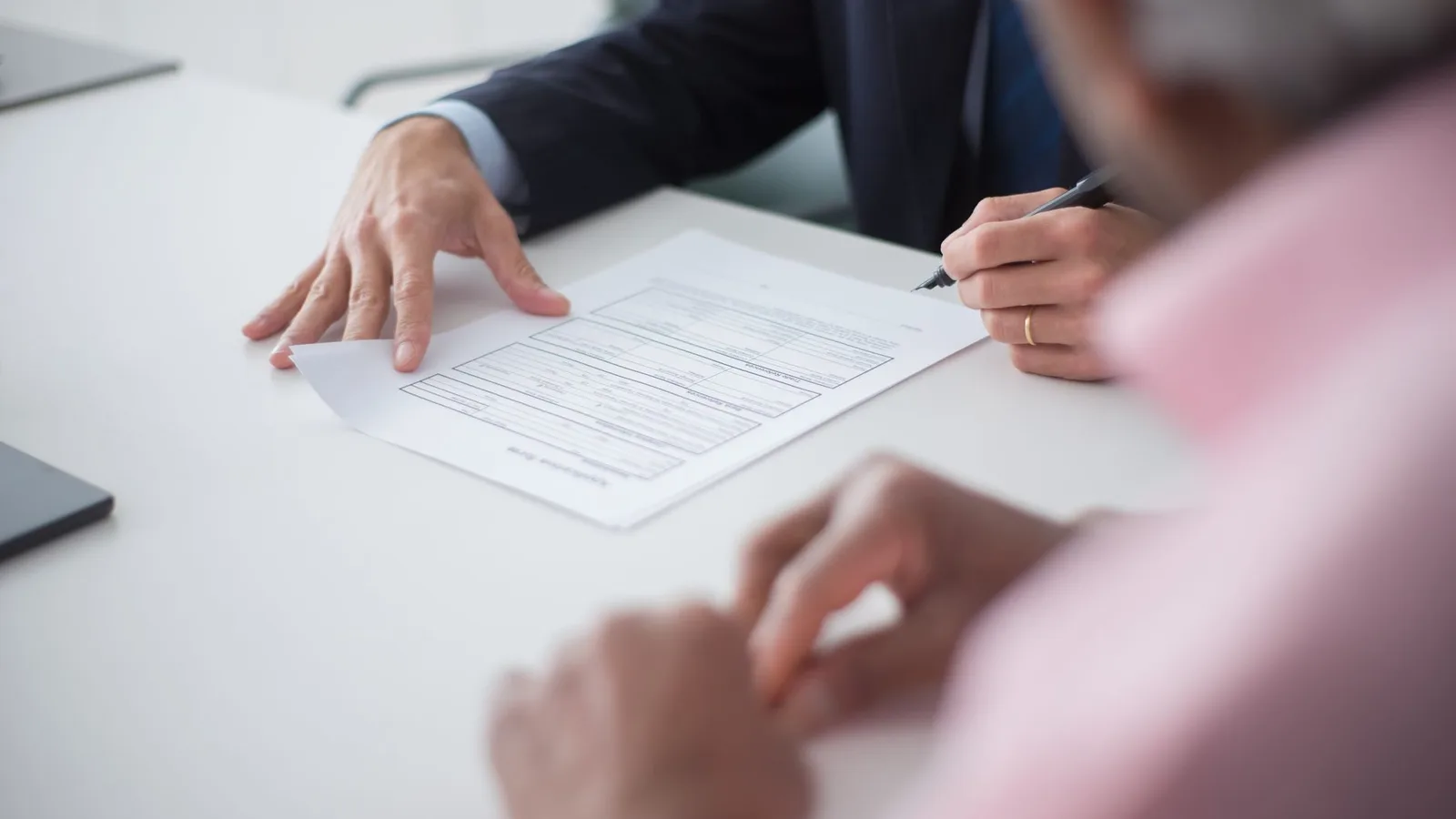 Two professionals engaging in a business meeting, signing documents for a consulting agreement