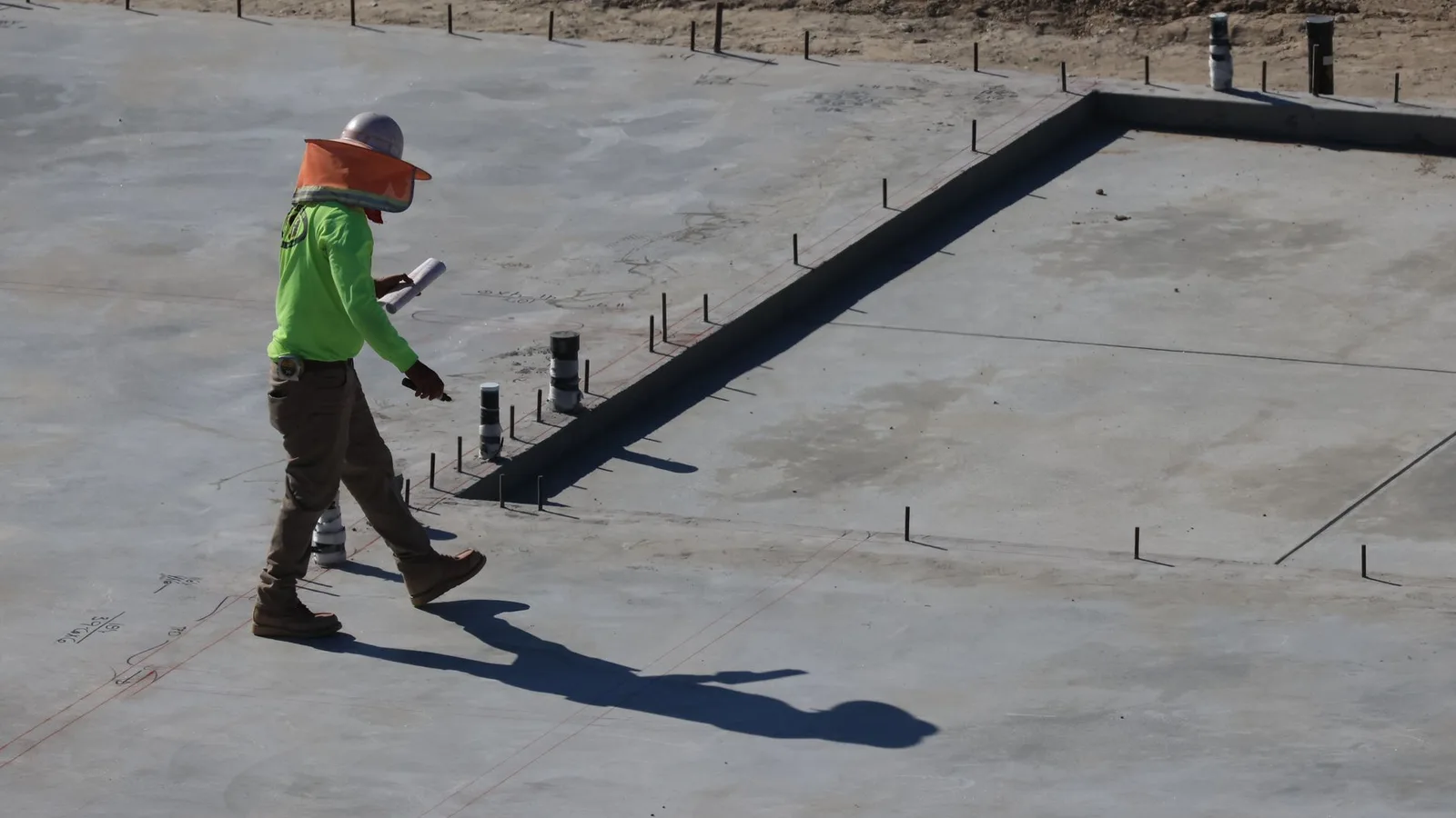 Engineer inspecting concrete slab at construction site in daylight