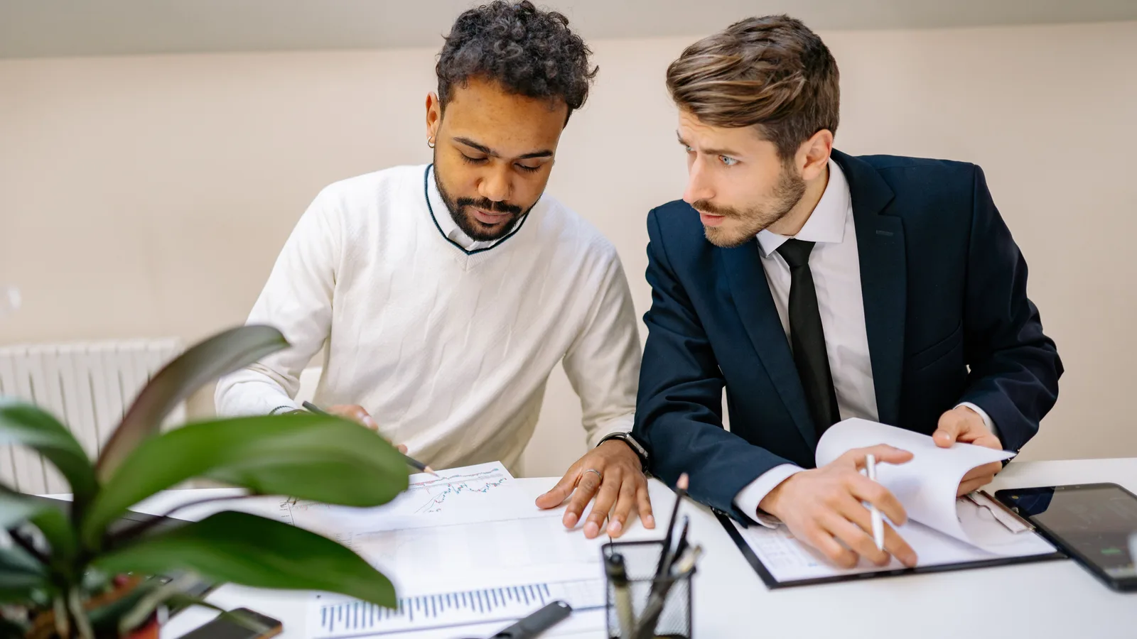 Two finance professionals reviewing a client's financial charts together at a desk