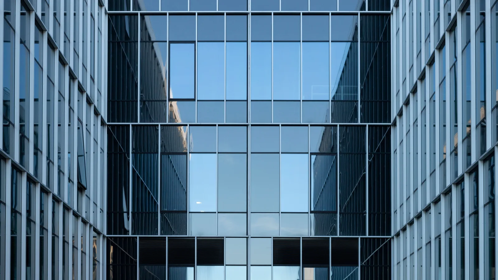 Reflective glass office building facade, representing mainstream bank lending self-employed borrowers often don't yet fit