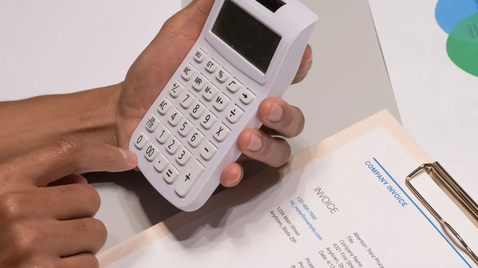 Close-up of hands holding a calculator over a company invoice, the kind of paperwork lenders accept as proof of income from self-employed borrowers