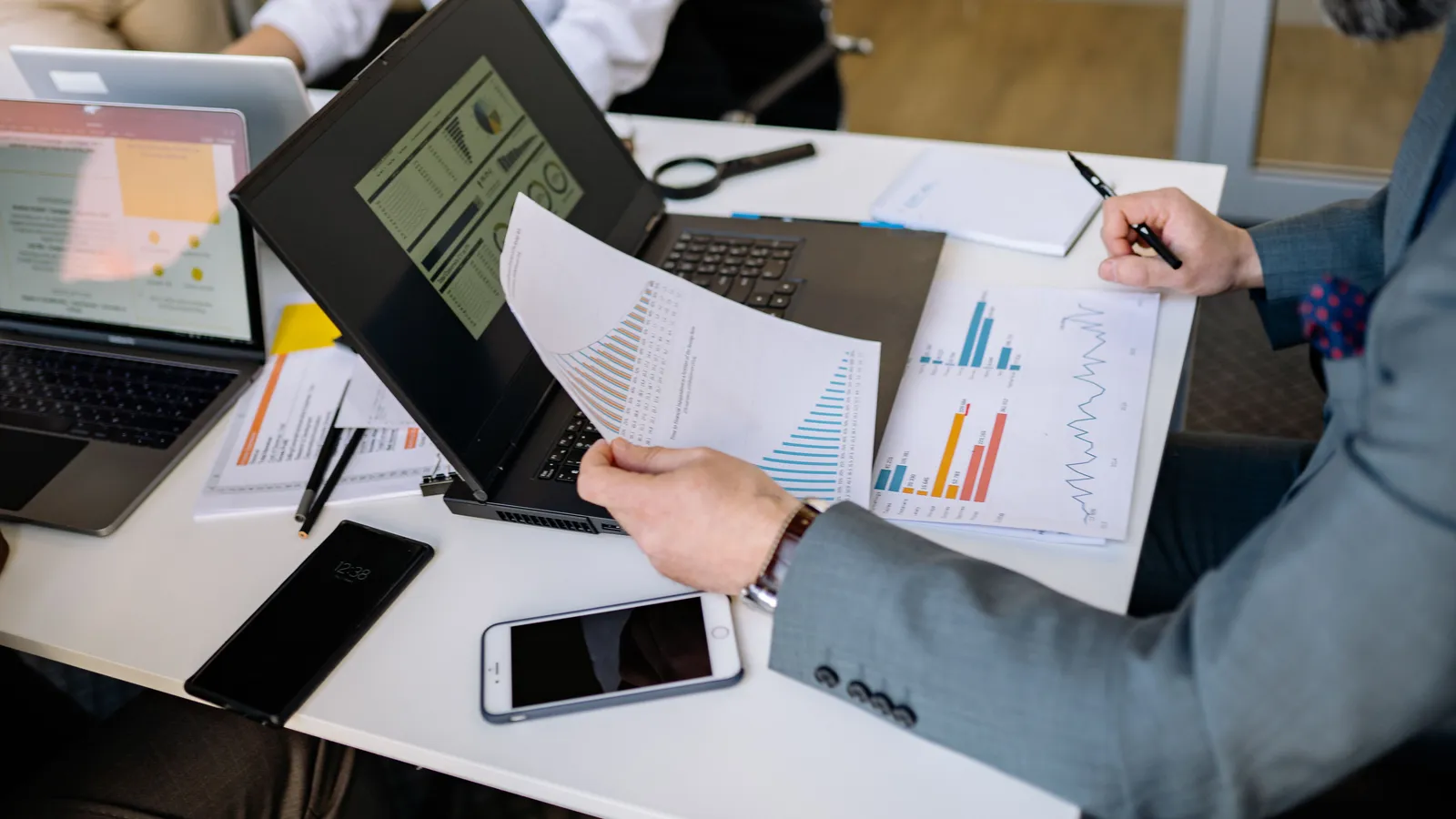 Two professionals reviewing financial charts and documents together at a laptop