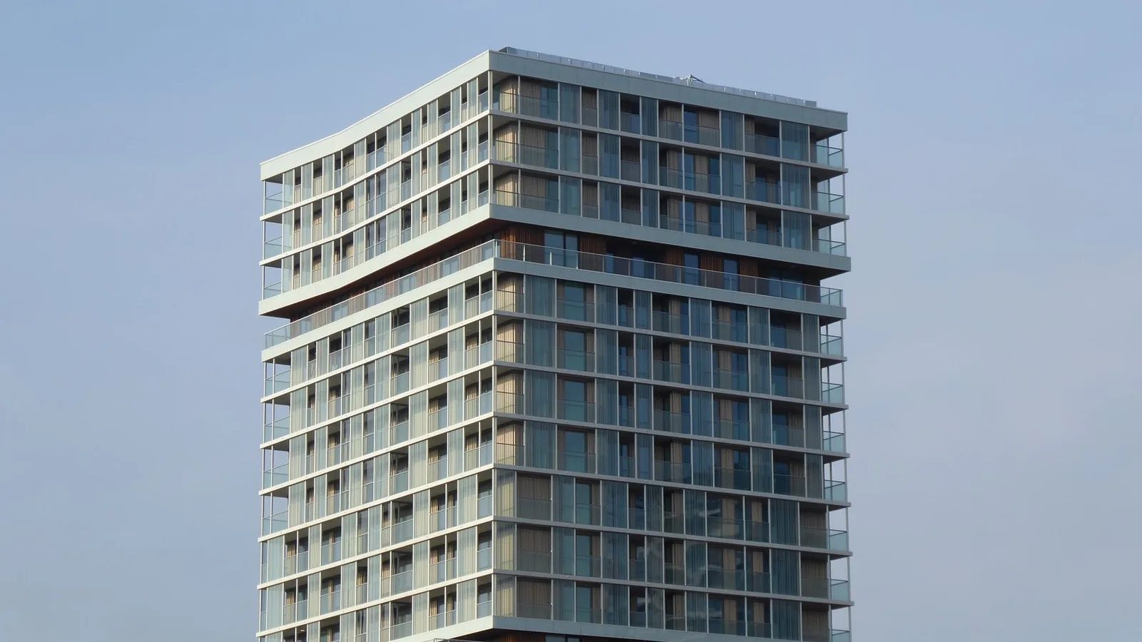 Contemporary high-rise building with glass facade under clear blue sky.