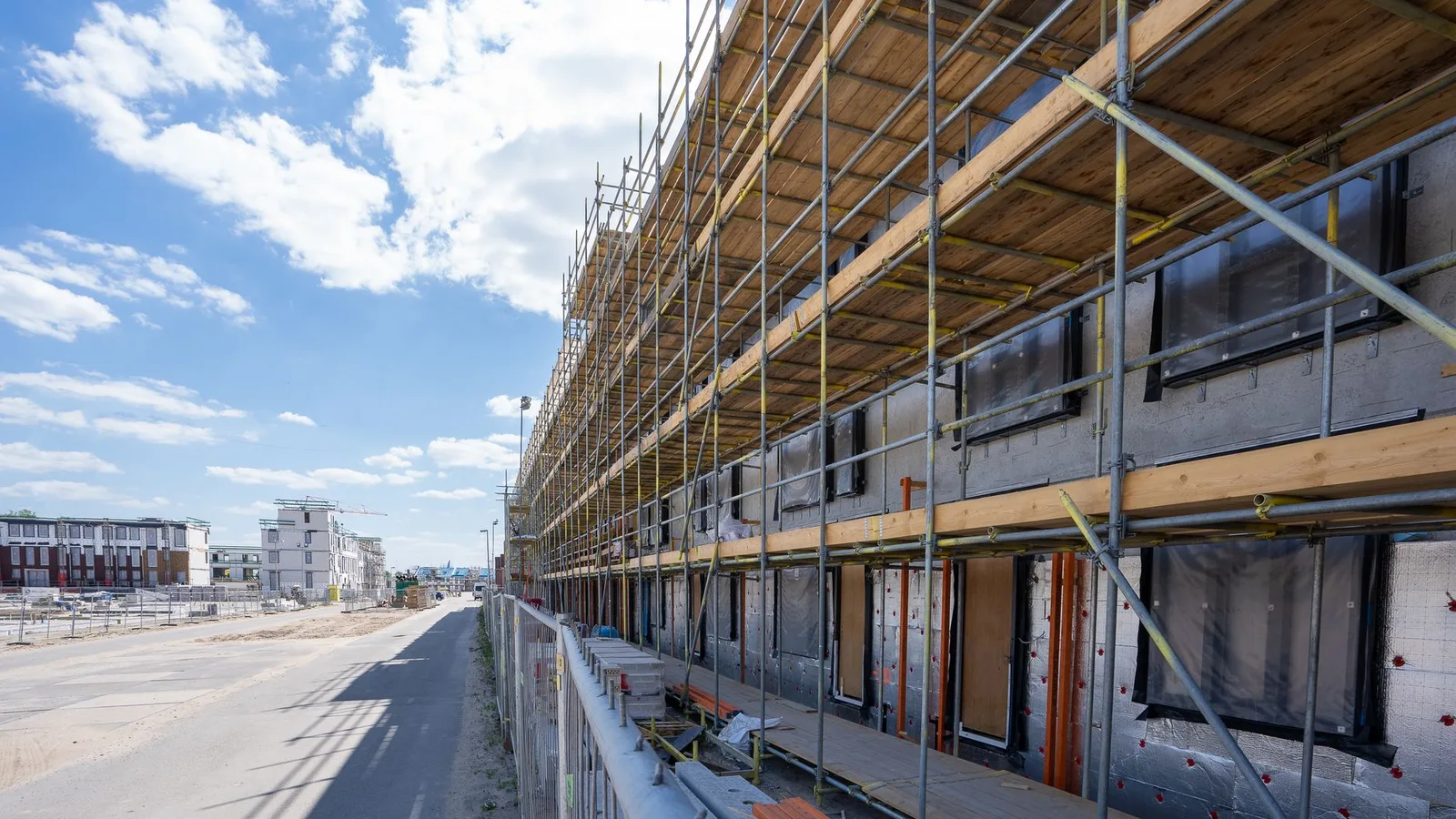 Scaffolding on building facade at urban construction site under bright blue sky.