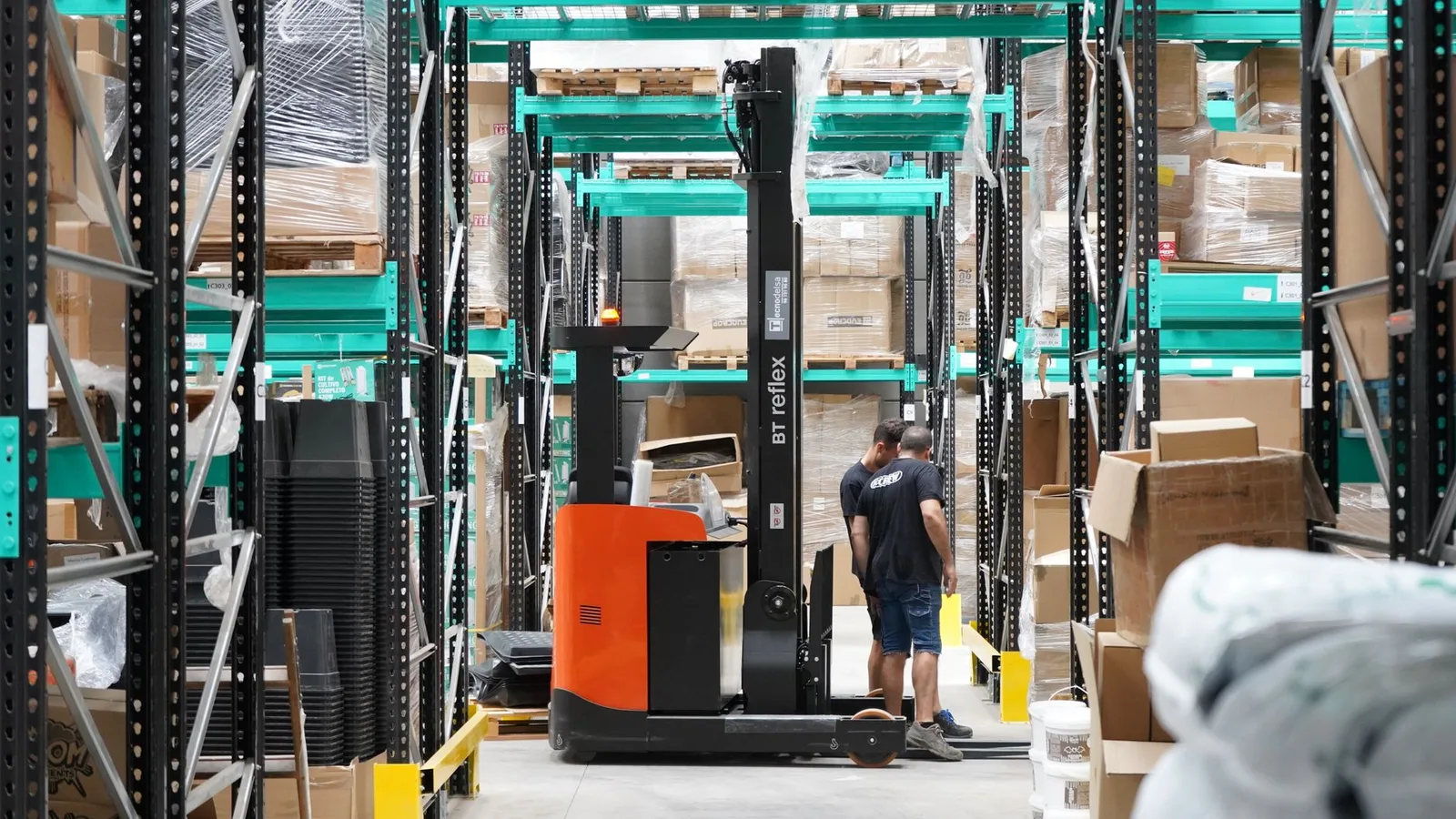 Commercial warehouse with workers and forklift organizing inventory pallets