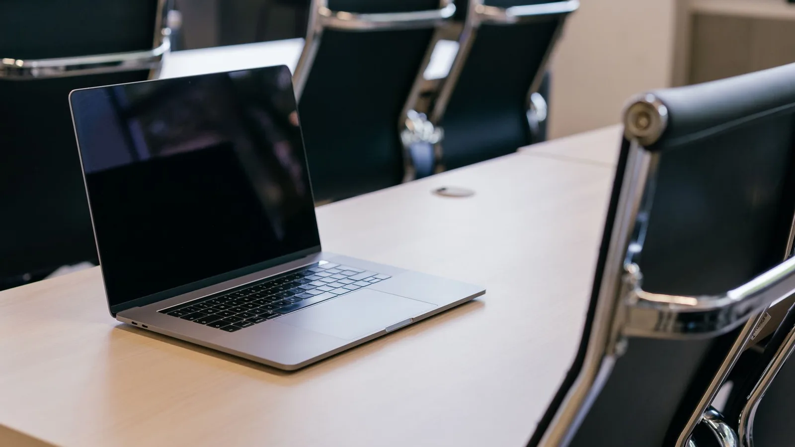 Modern office meeting room with wooden table and laptop