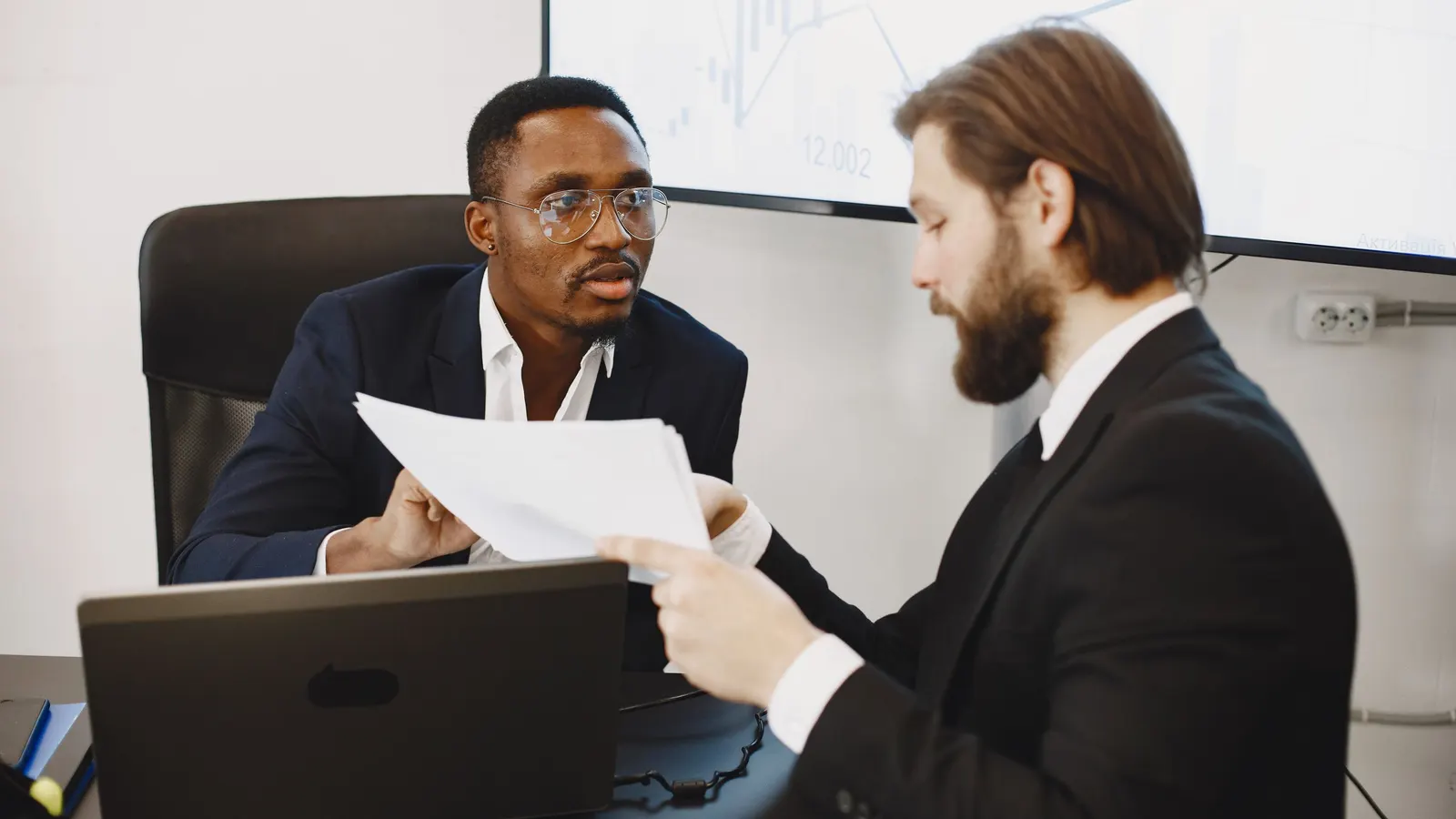 Two finance professionals reviewing documents together in an office