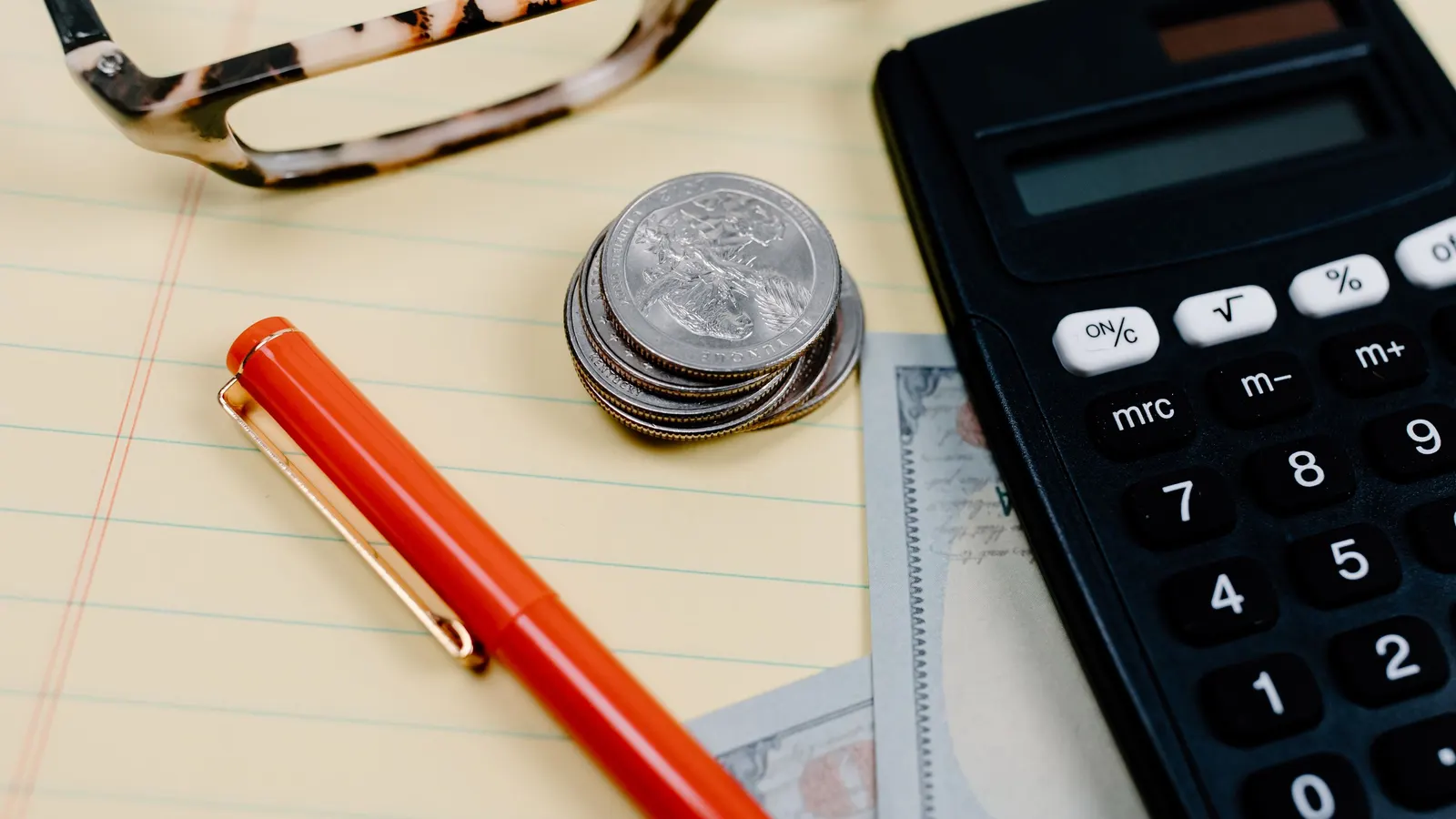 Calculator and loose change on a desk, representing the deposit and cost factors in truck finance
