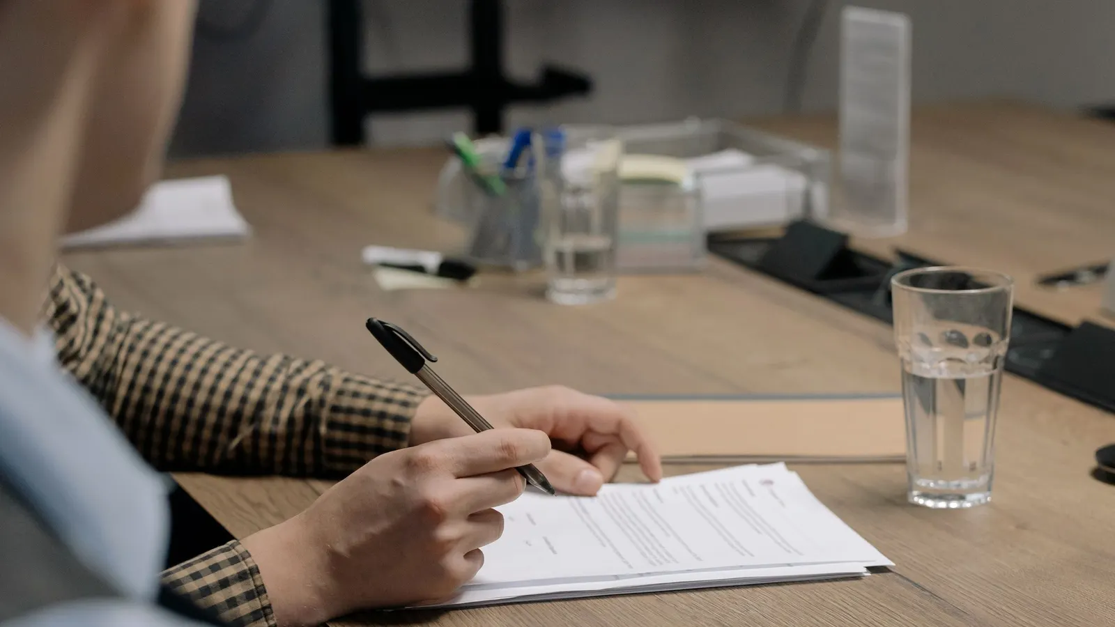 Close-up of a person signing finance documents at a desk