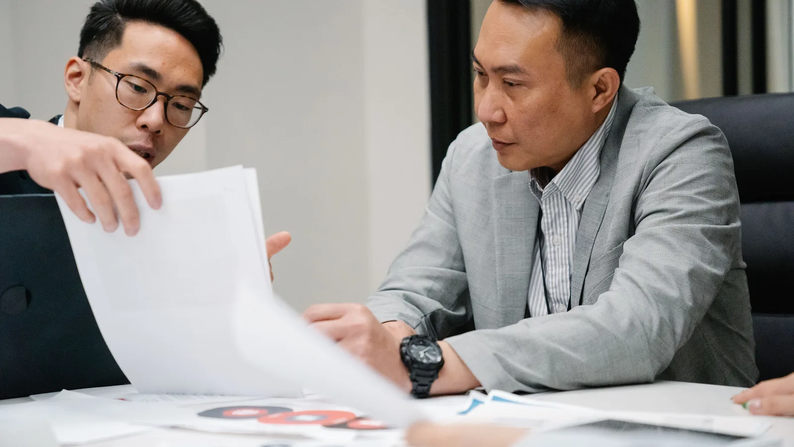 Two business professionals discussing paperwork in an office