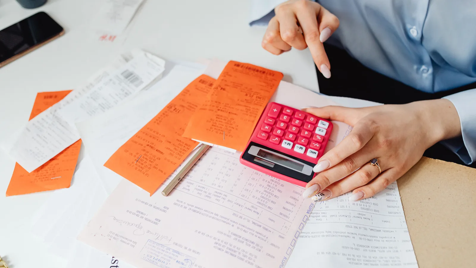 Business owner using a calculator while reviewing receipts at a desk