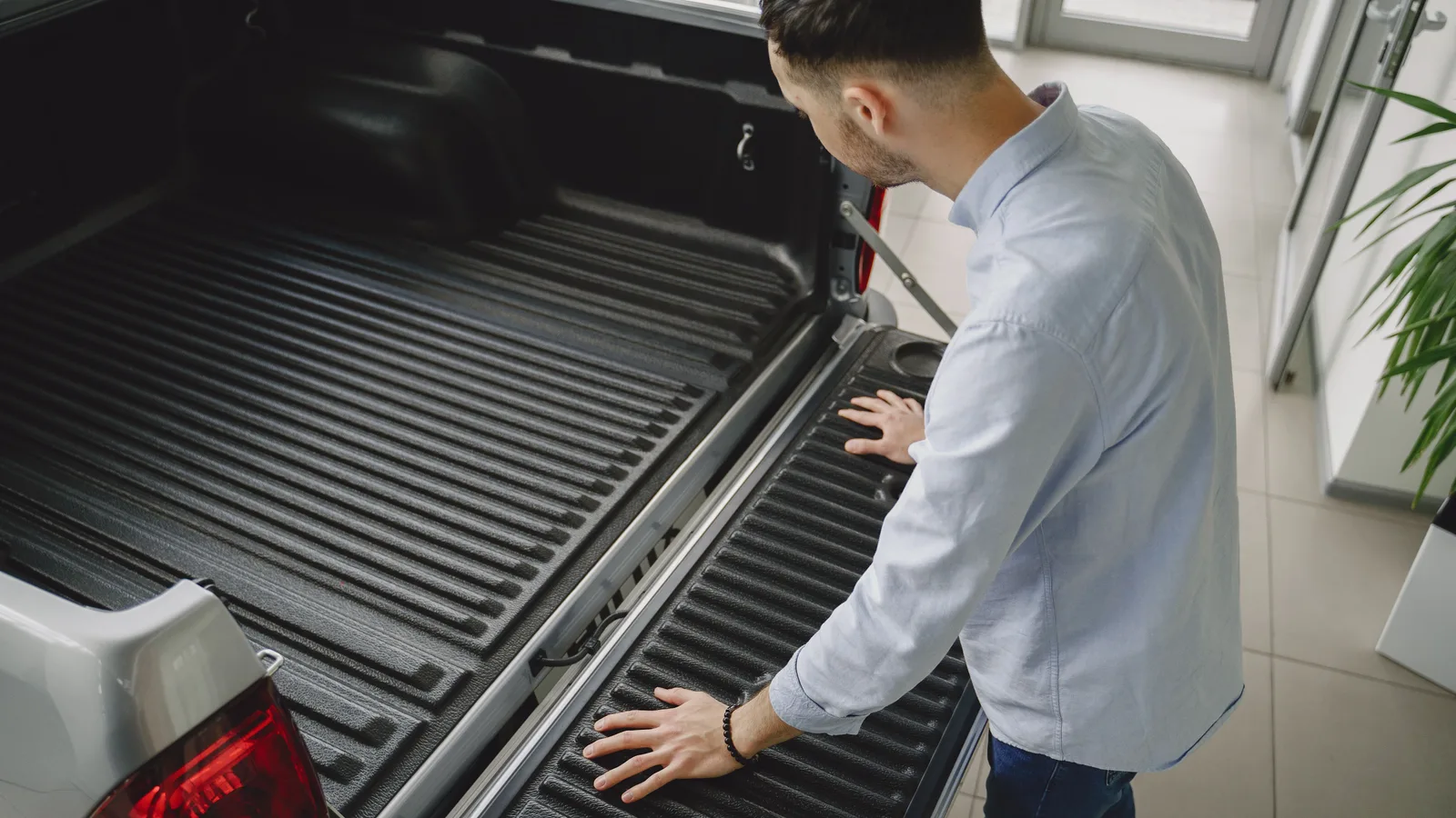 Tradesman checking the tailgate of a new pickup ute at a vehicle showroom
