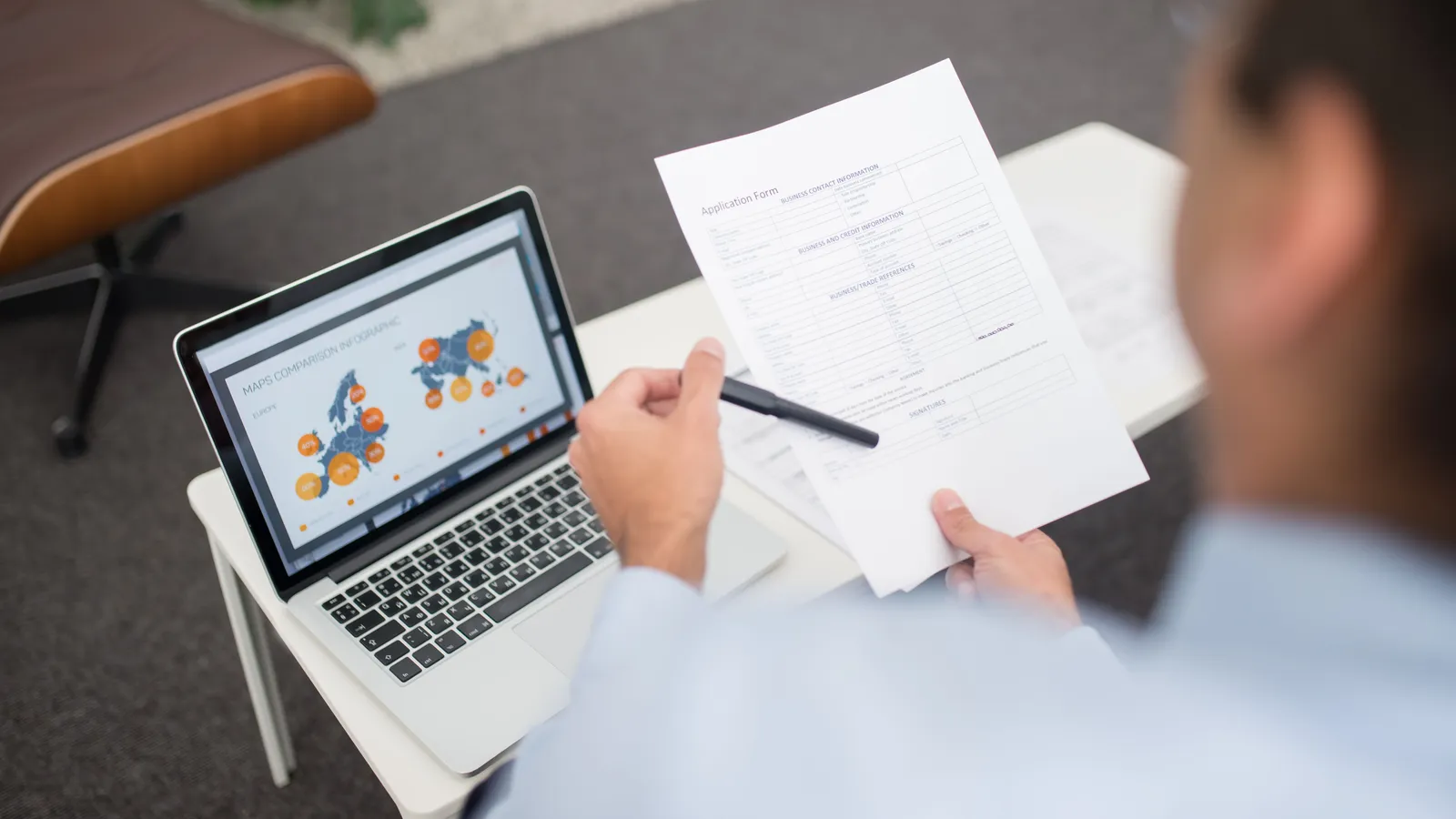 Businessman reviewing documents and data on a laptop in an office