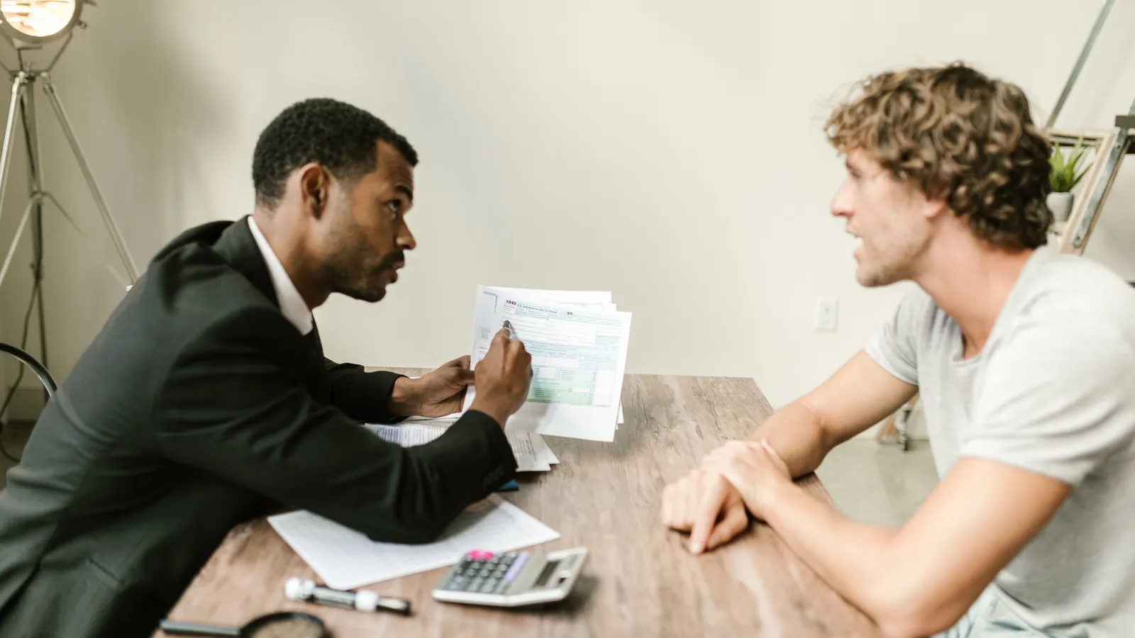 Financial advisor discussing paperwork with a client at a desk in a modern office