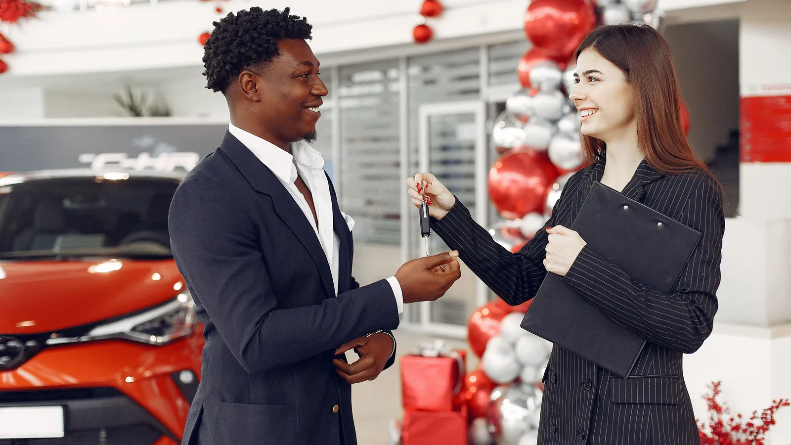 Car dealer handing over the keys to a new vehicle in a showroom