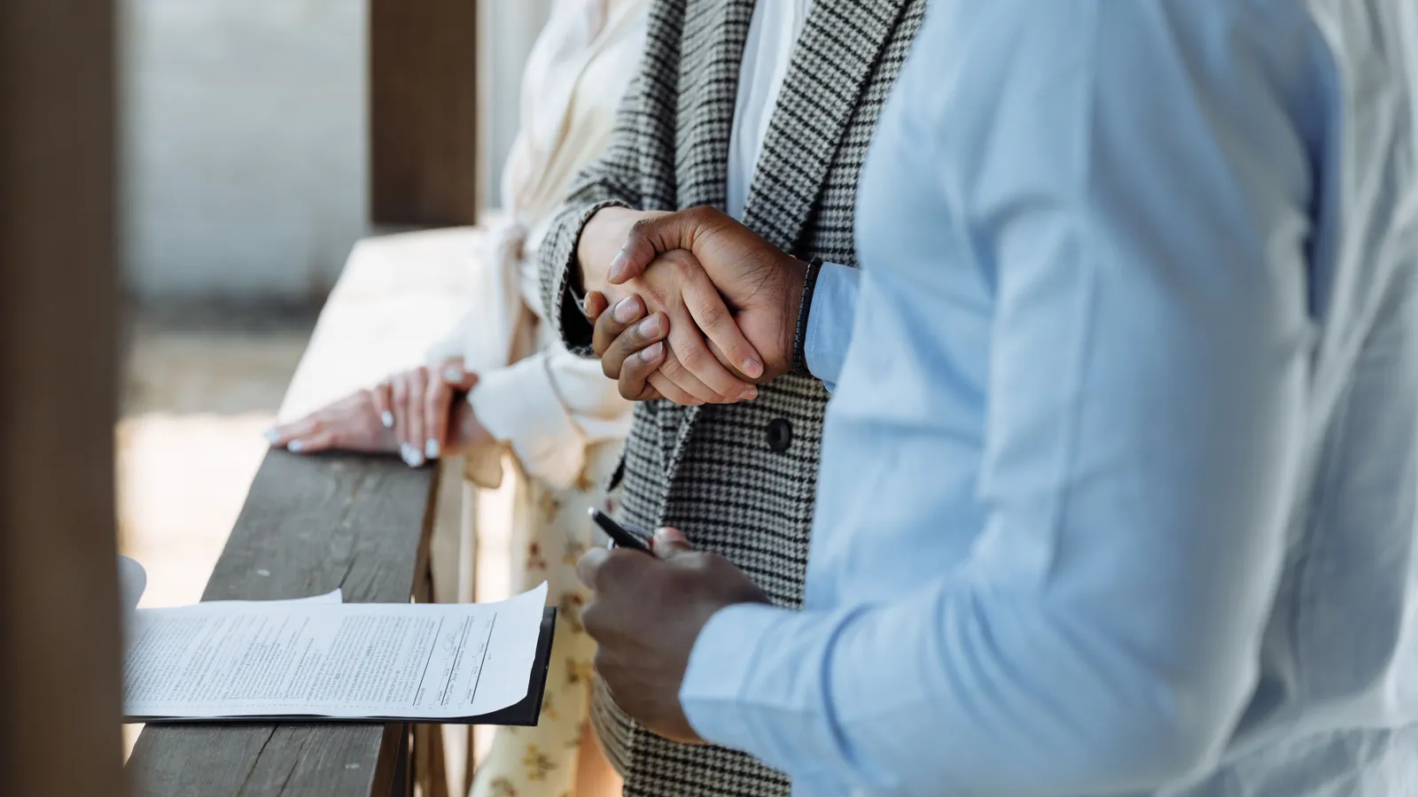 Close-up of hands shaking over a signed finance agreement at a desk