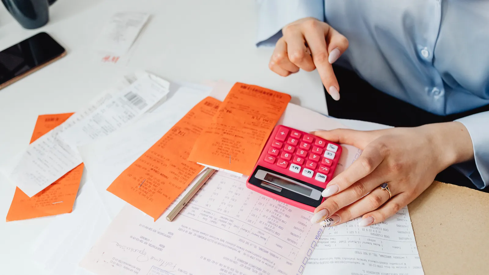 Business owner using a calculator while reviewing receipts at a desk